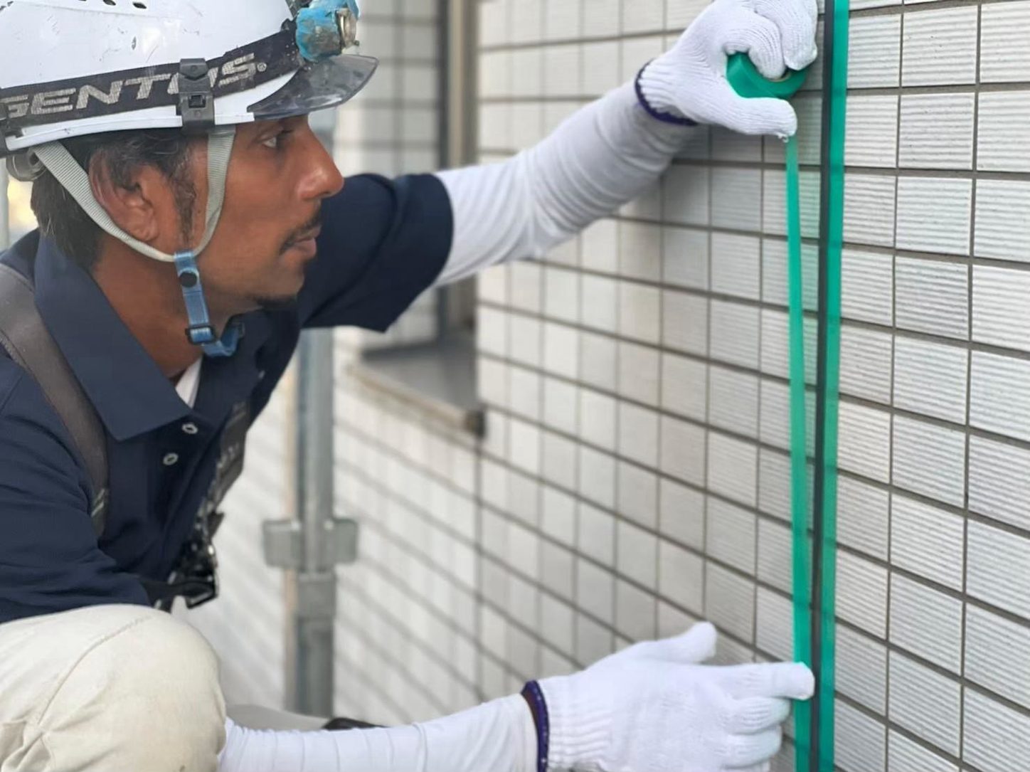 外壁のタイルを計測する職人